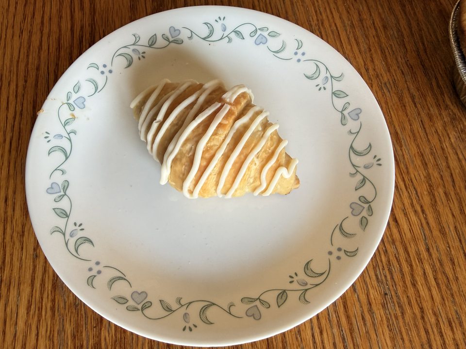 A strawberry croissant with icing drizzled on top